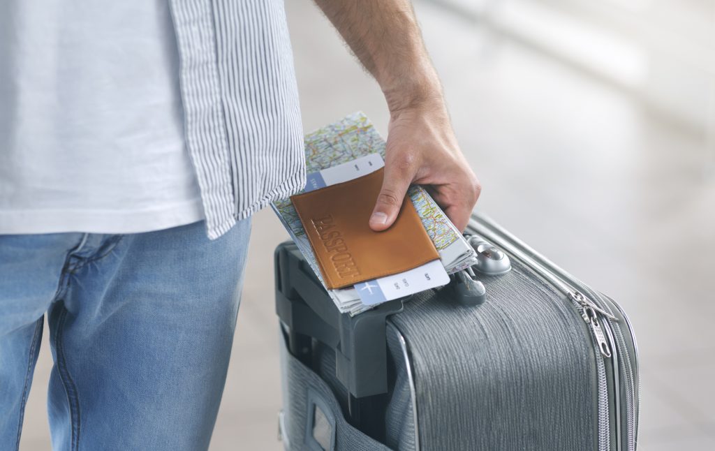 Vuelos baratos y hombre llevando maleta con pasaporte en mano